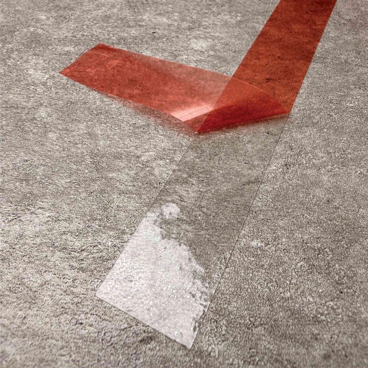 A close-up of double sided adhesive tape with a strip peeled back, placed on a textured grey concrete surface.